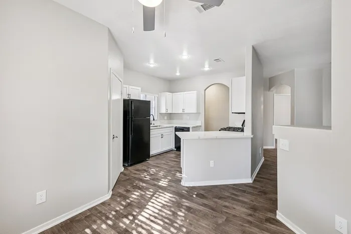 Modern kitchen with sleek black appliances, white cabinetry, and a spacious open layout featuring elegant wood flooring.