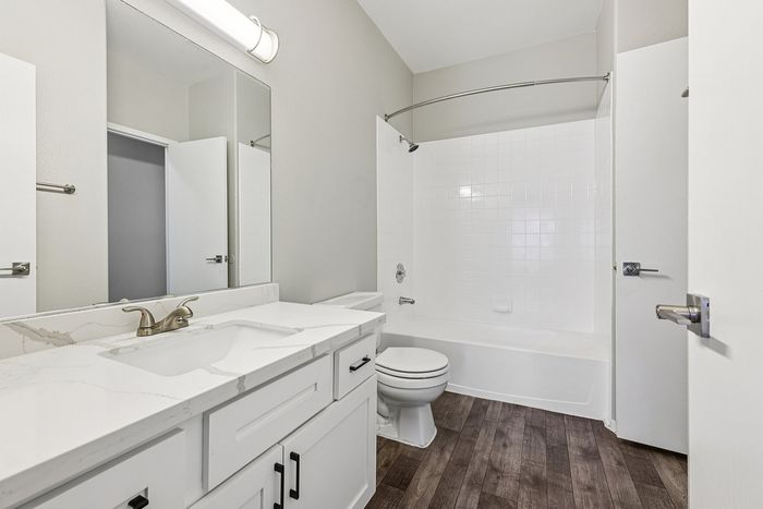 Elegant bathroom showcasing a chic marble countertop, modern lighting, and sleek wood flooring for a luxurious touch.