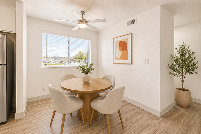 Bright and modern dining area with a round wooden table, four elegant chairs, and a potted plant, accented by a stylish abstract artwork and a ceiling fan.