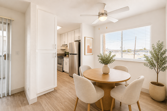 Bright dining area with a stylish round wooden table, plush chairs, and modern kitchen featuring sleek stainless steel appliances.