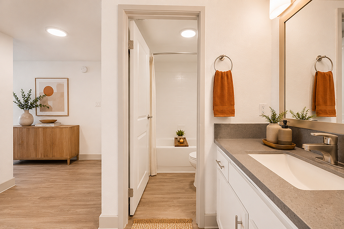 Modern bathroom with sleek vanity, elegant decor, and warm accents, leading to a stylish hallway in a charming apartment.