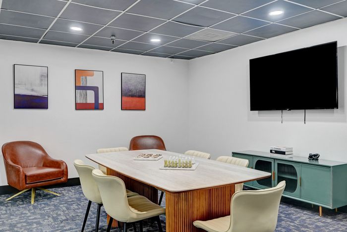 Modern meeting room with a sleek wooden table, stylish seating, and vibrant abstract art on the walls.