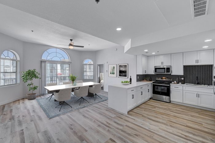 Bright, modern open-concept kitchen and dining area with large arched windows, sleek cabinetry, and stylish wood flooring.
