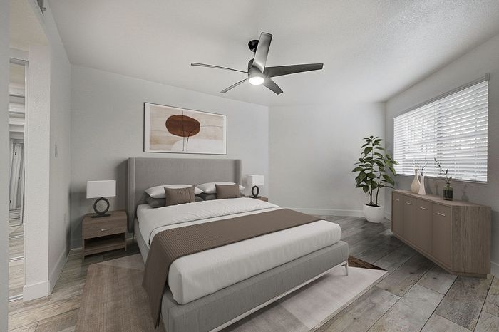 Modern bedroom with a plush bed, stylish ceiling fan, and natural light from large window, emphasizing comfort and relaxation.