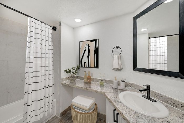 Elegant bathroom with a modern design featuring a spacious granite countertop, sleek black fixtures, and stylish art decor.