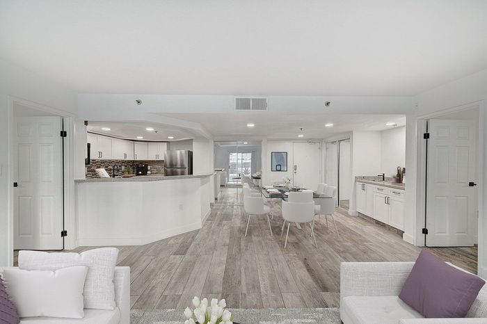 Elegant open-plan living room with hardwood floors, modern kitchen, and stylish dining area, perfect for entertaining.