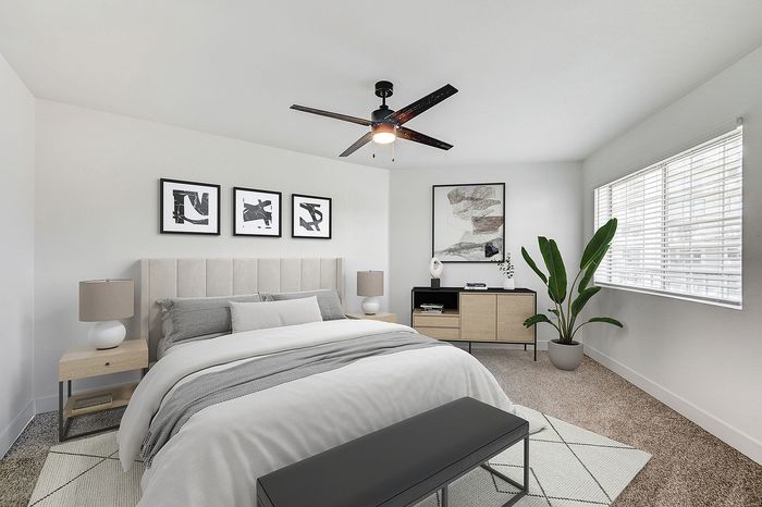 Inviting bedroom with chic decor, featuring a plush bed, modern art, and abundant natural light from a large window.