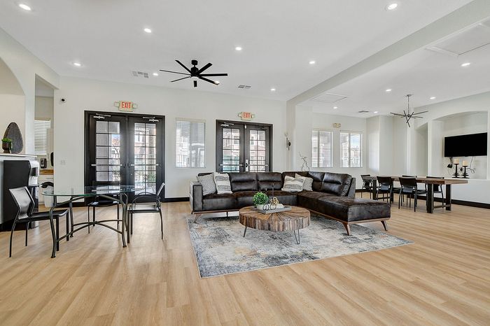 Modern open-concept living space featuring a chic leather sectional sofa, elegant wood flooring, and ample natural light.