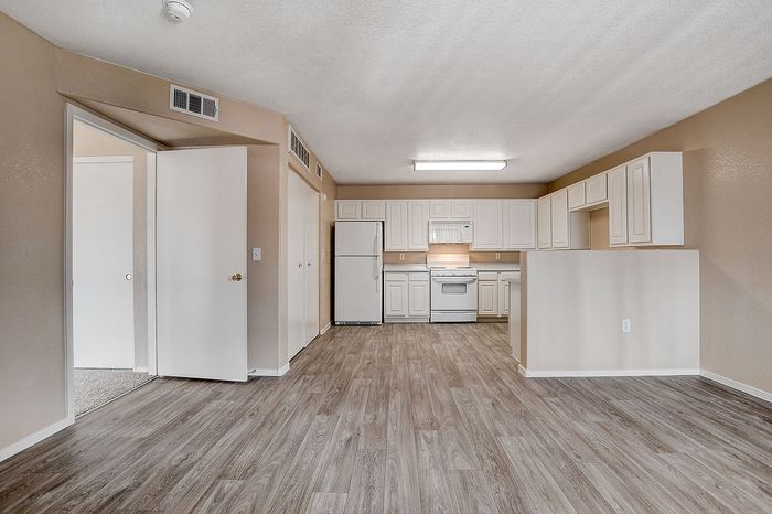 Bright and inviting open-concept kitchen and living area with modern flooring and abundant cabinetry.