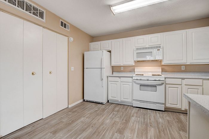 Modern kitchen with sleek white cabinets, spacious countertops, and stylish wood flooring, perfect for culinary creativity.