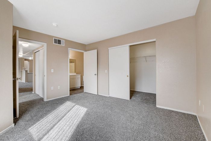 Bright bedroom with plush carpeting, spacious closet, and inviting neutral walls.