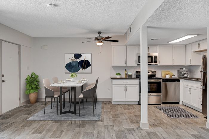 Modern open-concept kitchen and dining area with chic decor, featuring sleek white cabinetry, stainless steel appliances, and a stylish dining set.