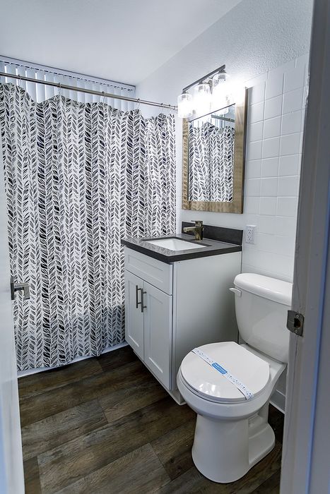 Modern bathroom featuring elegant vanity, stylish lighting, and decorative shower curtain with a chic leaf pattern.