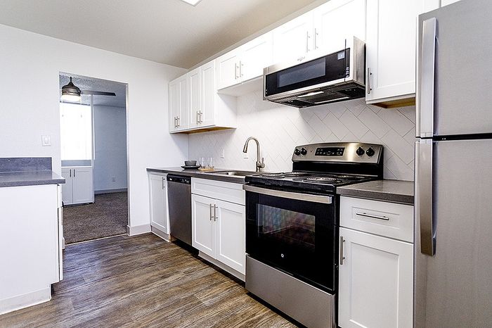 Modern kitchen with sleek stainless steel appliances, elegant white cabinetry, and hardwood floors.