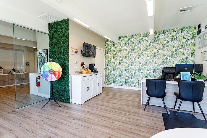 Vibrant office space with a stylish tropical wallpaper, modern furnishings, and a playful spin-the-wheel feature, offering a welcoming and creative atmosphere.