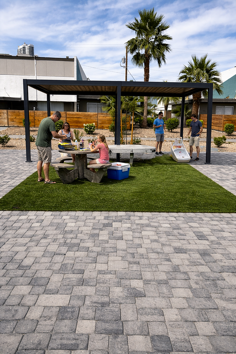 Inviting outdoor patio with a modern pergola, lush greenery, and a picnic area perfect for gatherings and relaxation.