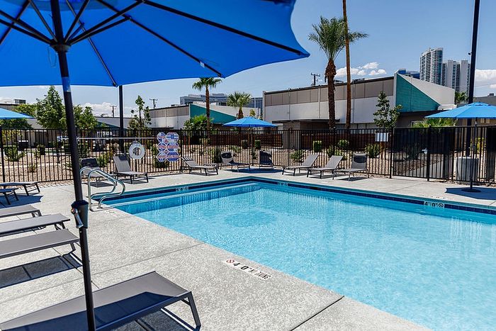 Inviting outdoor pool area with elegant lounge chairs and vibrant blue umbrellas, perfect for relaxation and leisure.