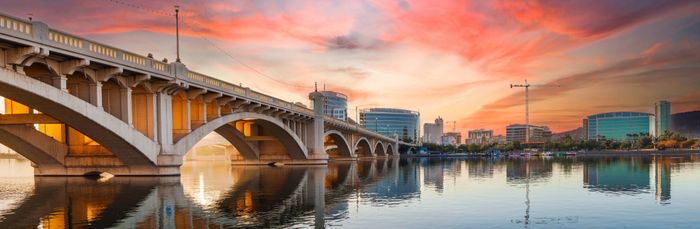 Photograph of a bridge near our apartments in Tempe, featuring a colorful sunset and a view of the city skyline.