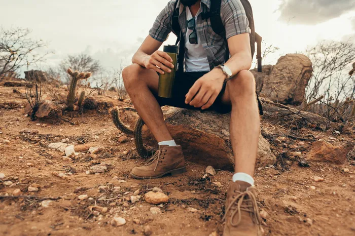 Stock photo of someone hiking in the desert and drinking water.
