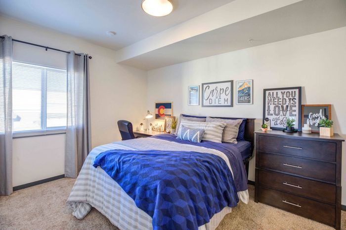 Model apartment bedroom with a full size bed, dresser, desk, and desk chair at Union on Alley.