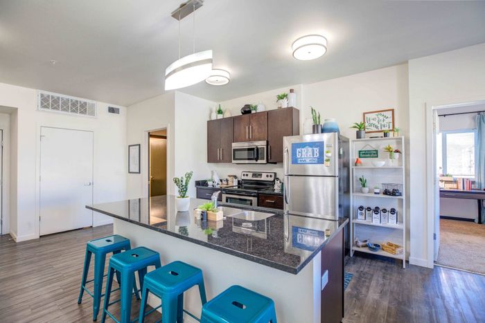 Model apartment kitchen with dark wood cabinets, granite countertops, and stainless steel appliances at Union on Alley in Fort Collins.