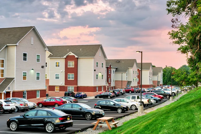 The parking lot at our student apartments near Syracuse University, featuring cars parked in the parking lot.