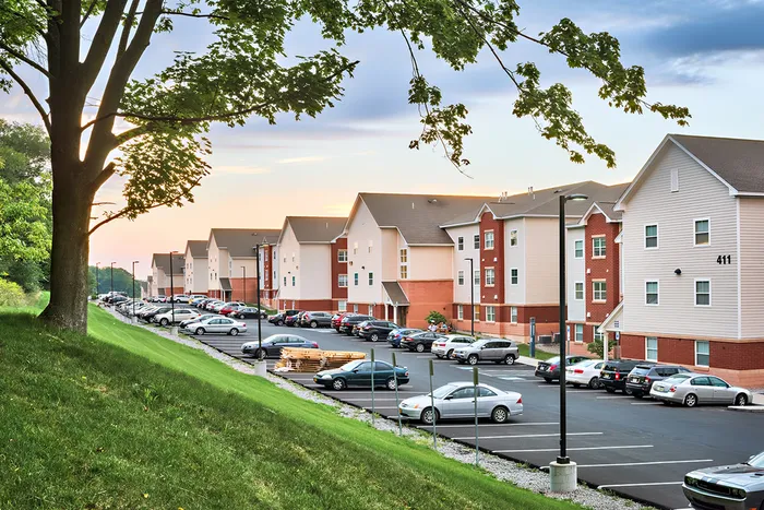 The parking lot at our student apartments near Syracuse University, featuring cars parked in the parking lot.