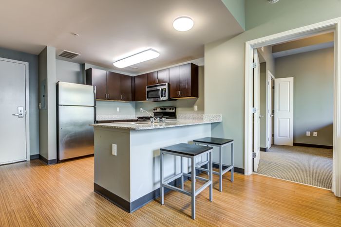 Model kitchen at our apartments for rent in Syracuse, featuring wood grain floor paneling and stainless steel appliances.