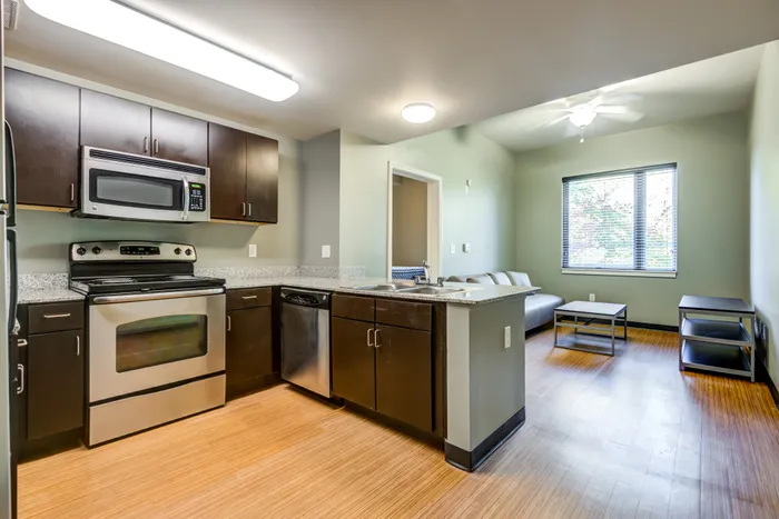 Model living room at our apartments for rent in Campus West, featuring wood grain flooring and a flat screen TV.