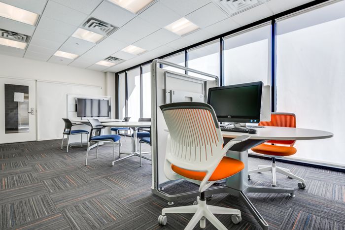 Co working space and offices at our apartments for rent in Syracuse, NY, featuring carpeted flooring and computers on desks.