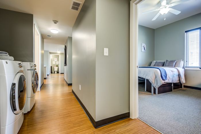 View of a bedroom, the hallway with washer and dryer at Campus West apartments near Syracuse University.