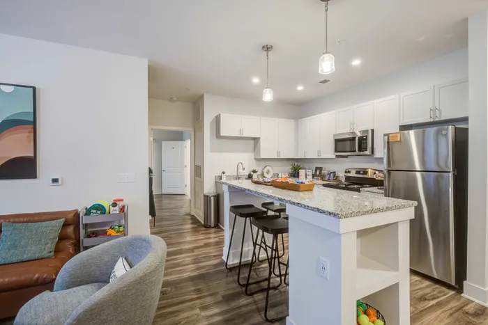 Model dining room and kitchen at our student apartments in Blacksburg, featuring wood grain floor paneling.
