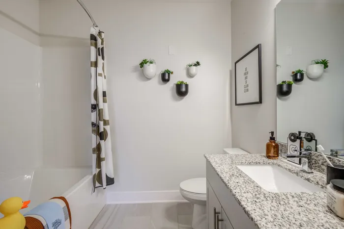 Model bathroom at our student apartments in Blacksburg, featuring granite patterned countertops and a bath / shower combo.