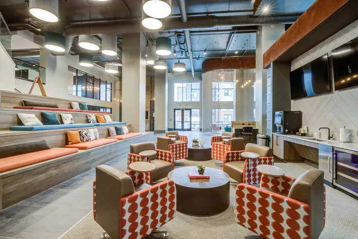 Resident lounge at our student apartments in Blacksburg, VA, featuring cushioned chairs and a well lit, spacious lobby.