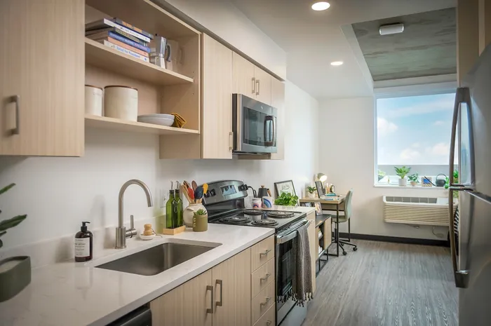 Model apartment kitchen with light wood cabinets and stainless steel appliances