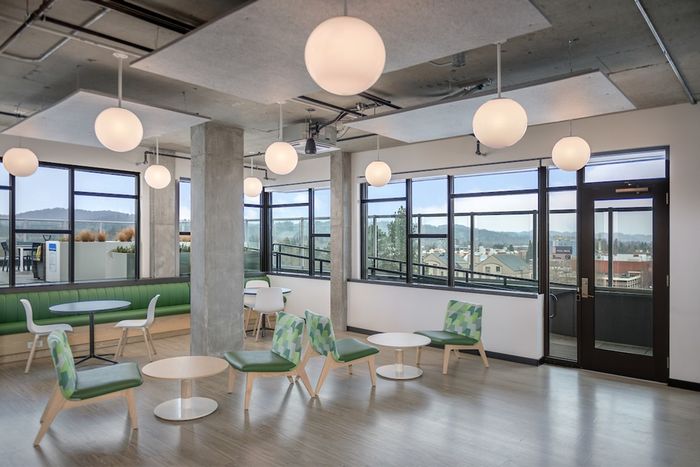 Community clubhouse with tables, chairs, and large windows looking out at the city of Eugene