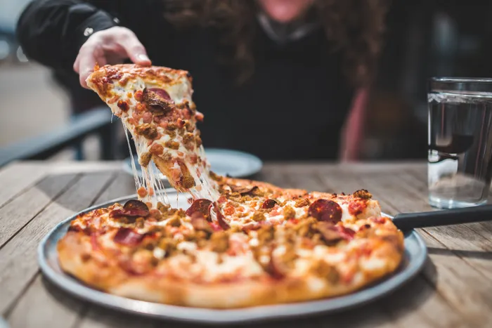Someone grabbing a slice of pizza