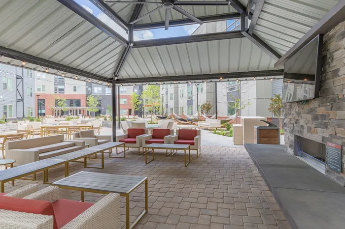 Outdoor lounge at our apartments for rent in Blacksburg, featuring a shade structure, outdoor seating, and view of the pool.