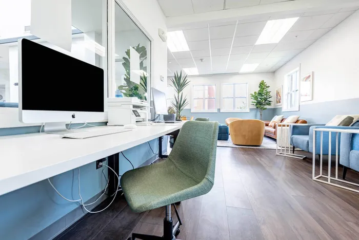 Co working space at our student apartments near Syracuse University, featuring desks, chairs, and a coffee machine.