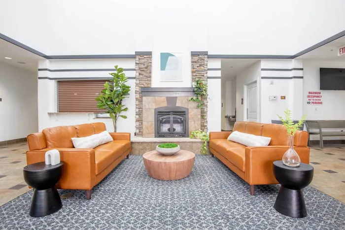 Lobby and lounge at our student apartments in Syracuse, featuring a front desk, tiled flooring, and couches.
