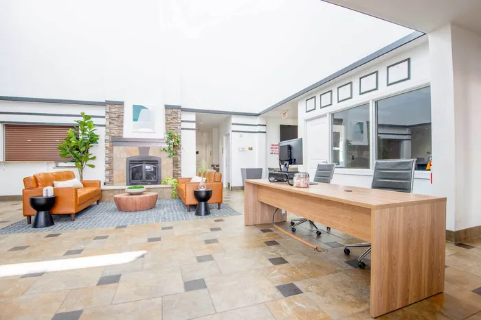 Lobby and lounge at our student apartments in Syracuse, featuring a front desk, tiled flooring, and couches.