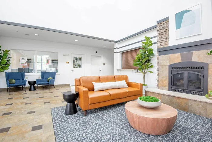 Lobby and lounge at our student apartments in Syracuse, featuring a front desk, tiled flooring, and couches.