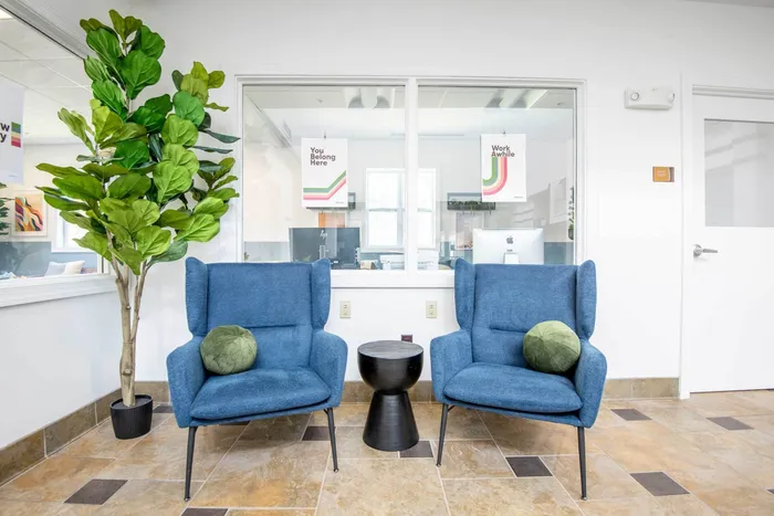 Lobby and lounge at our student apartments in Syracuse, featuring a front desk, tiled flooring, and couches.