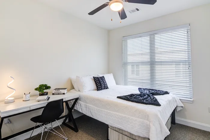 Model bedroom at our apartments for rent in Storrs, CT, featuring carpeted flooring and windows with blinds.