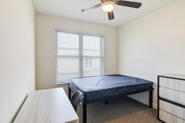 Model bedroom at our apartments for rent in Storrs, CT, featuring carpeted flooring and windows with blinds.
