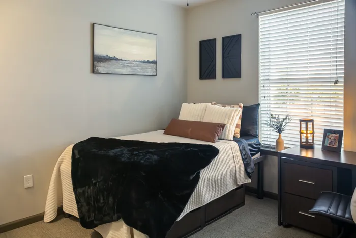 Furnished bedroom with window at College View Mississippi State student apartments.