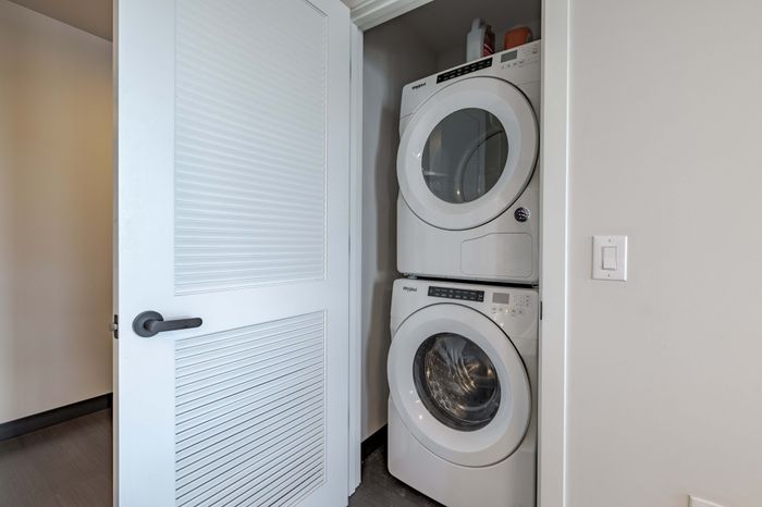 Model apartment laundry closet with large stacked washer and dryer