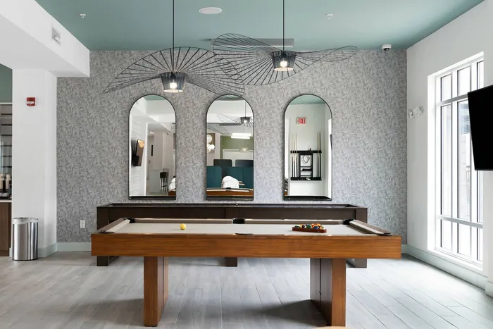 Student lounge at The Blake in Kennesaw, GA that has a pool table and shuffleboard with lots of natural lighting from the large floor to ceiling window.