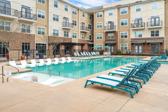 The pool area at The Blake apartments in Kennesaw with plenty of lounge chairs around the pool and a set of in water lounge chairs.