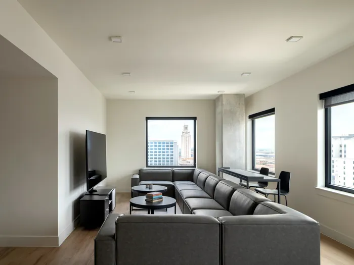 Model apartment living room at Union on 24th with large couch, coffee tables, and a large flat screen tv and windows looking out to the city of Austin.